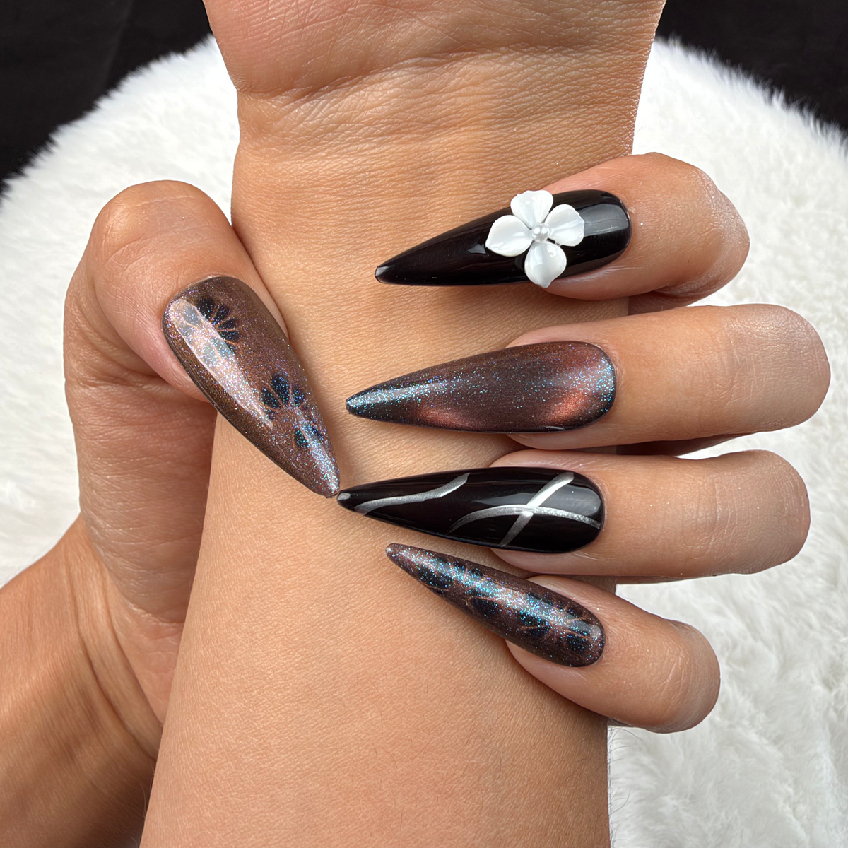 Close-up of hands wearing Smoky Bloom black and smoky grey stiletto press-on nails with a white 3D flower