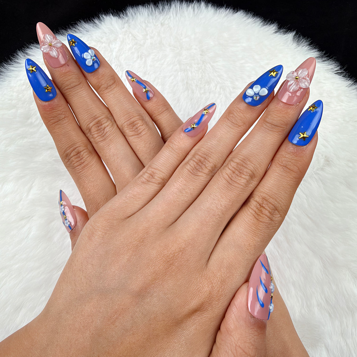 Hands wearing Blue Starlight cobalt blue and pink floral star almond press-on nails