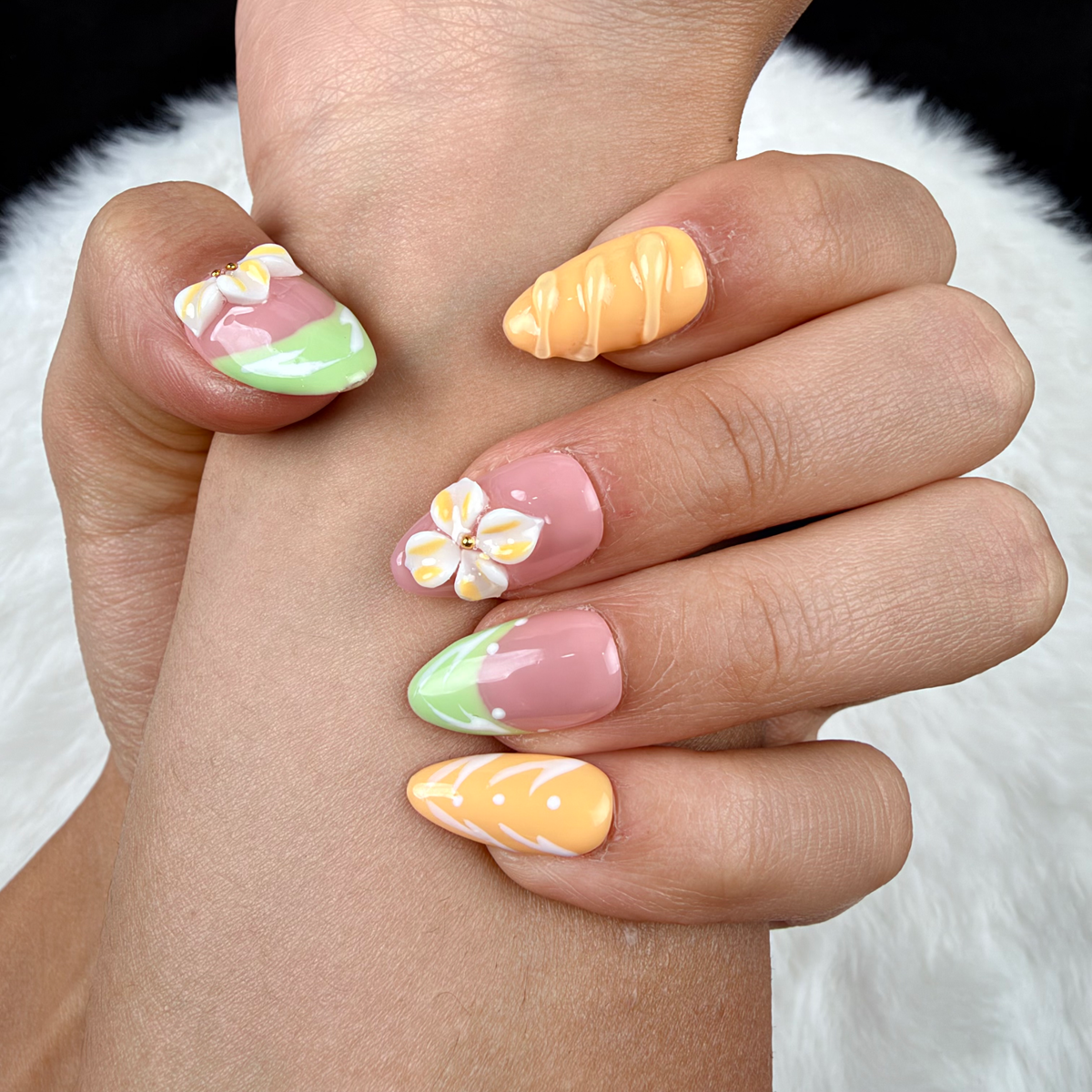 Detail shot of Citrus Blossom mint, pink and orange floral almond press-on nails on hand