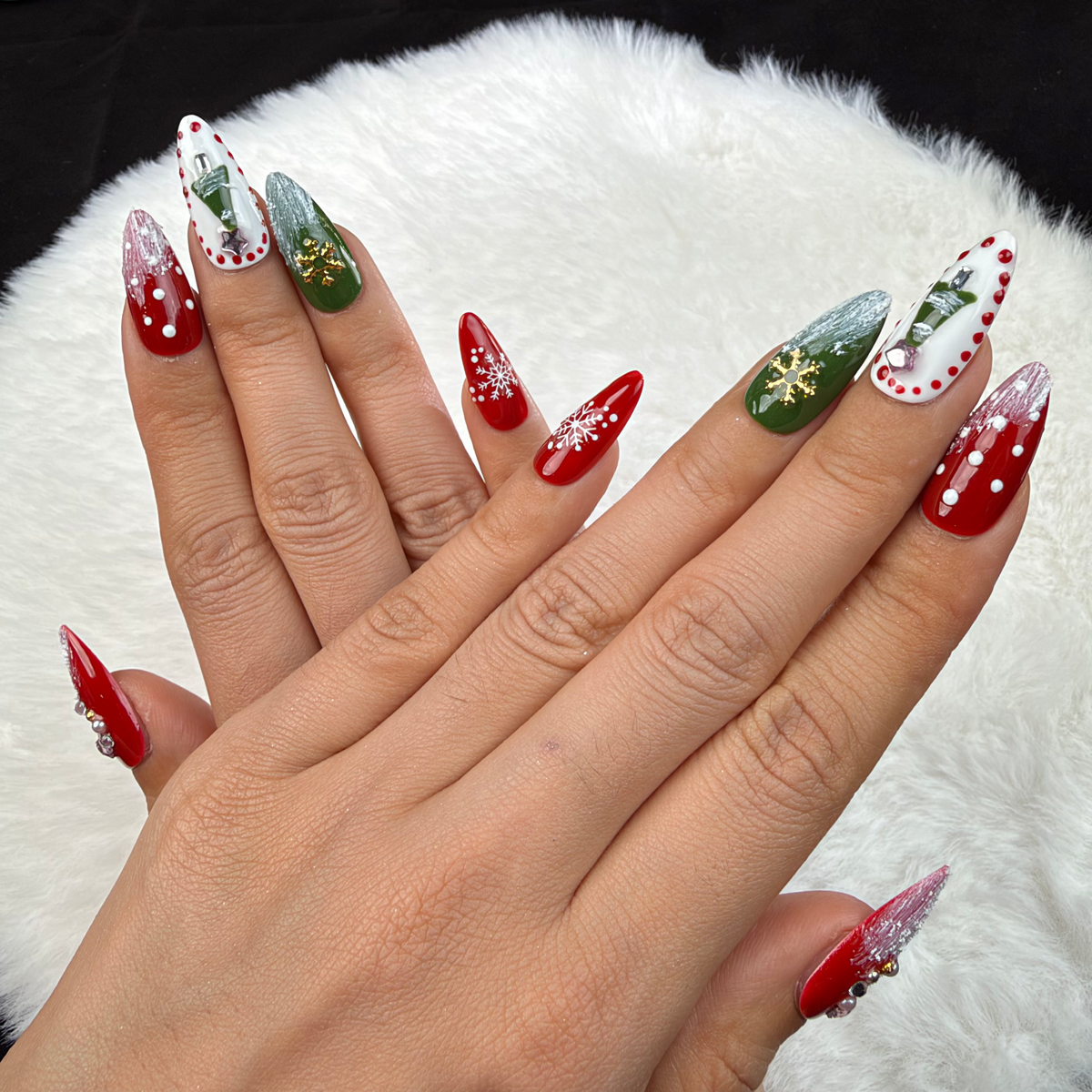 Detail shot of Festive Garland red, green and white Christmas almond press-on nails with wreaths and snowflakes on hand