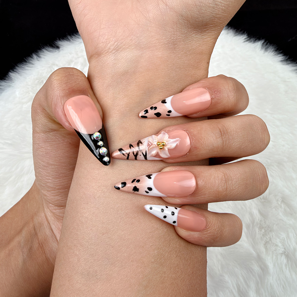 Detail shot of Noir Detail black and nude graphic French tip almond press-on nails on hand