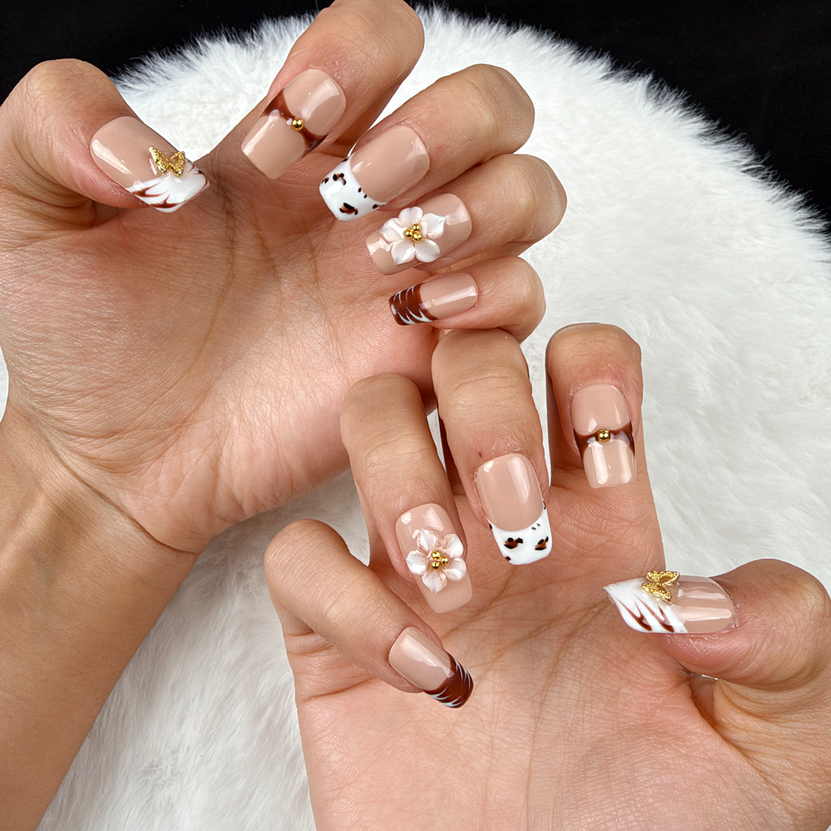 Close-up of hands wearing Caramel Bouquet brown, white and nude floral square press-on nails