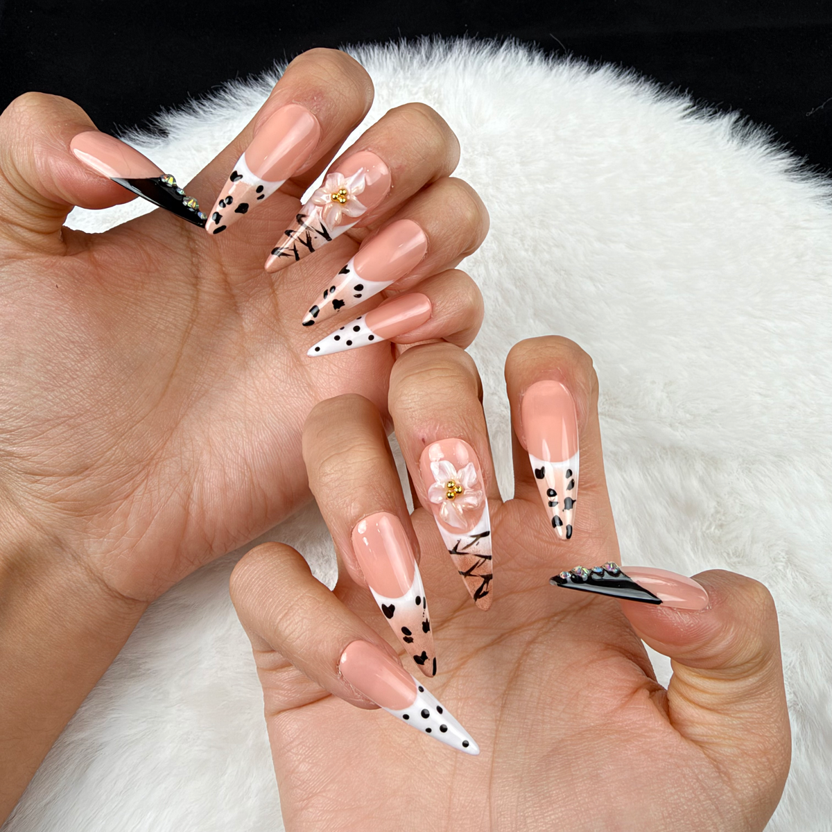 Close-up of hands wearing Noir Detail black and nude graphic French tip almond press-on nails
