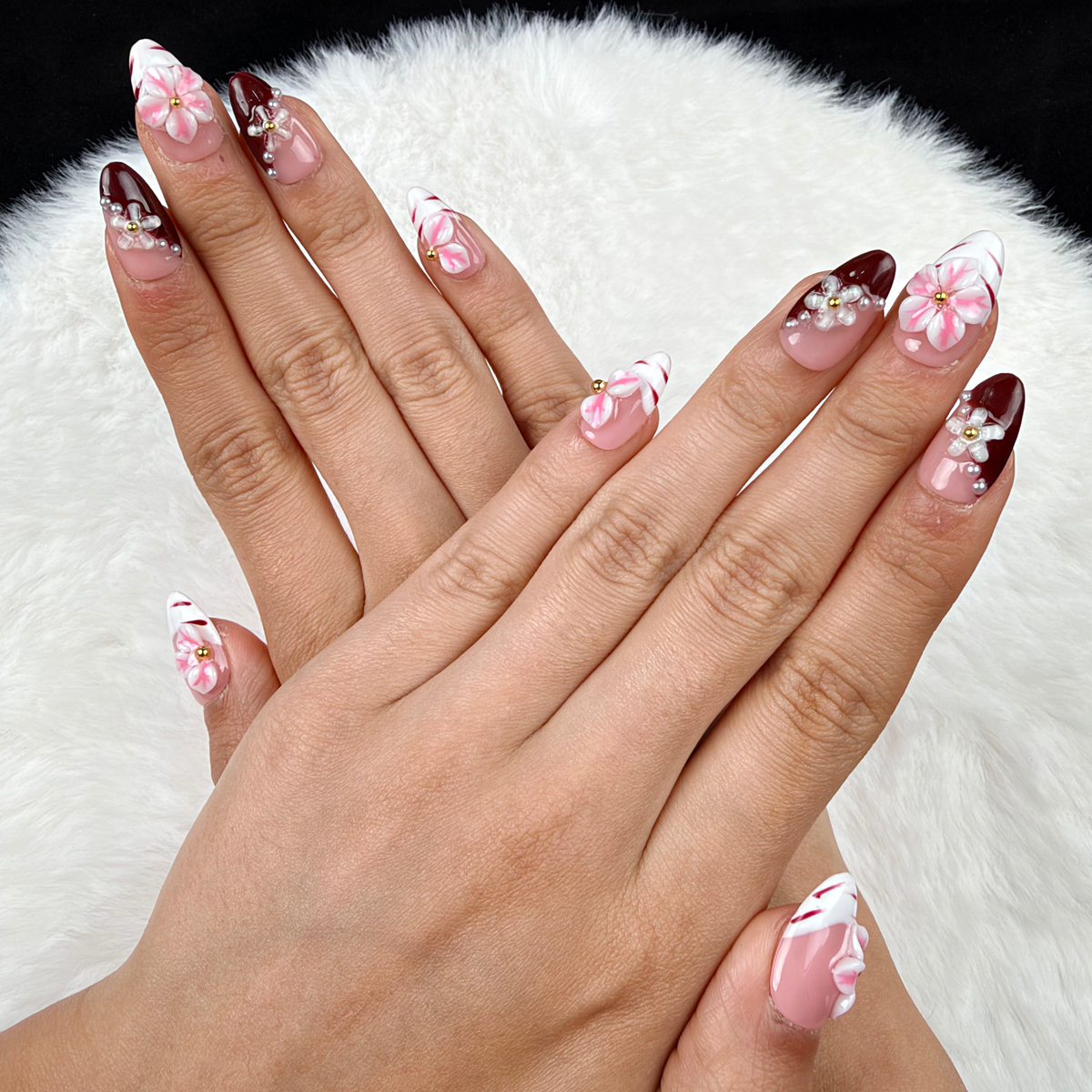 Hands wearing Rose Marble pink floral and burgundy French tip almond press-on nails