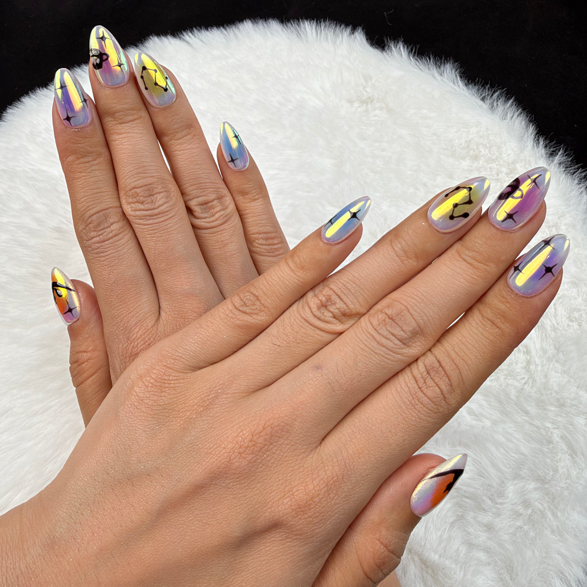 Hands wearing Aurora Signs iridescent celestial almond press-on nails