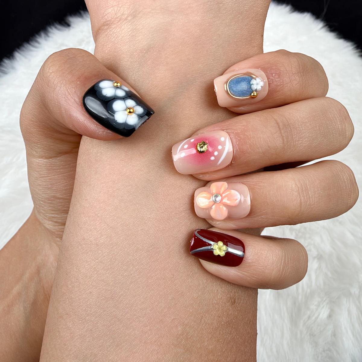 Detail shot of Blossom Mosaic nude, burgundy and black floral square press-on nails on hand