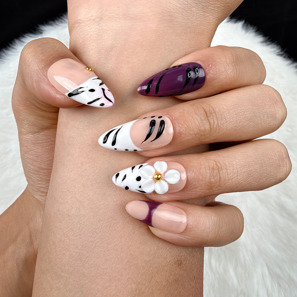 Detail shot of Plum Safari plum, black and white zebra print floral almond press-on nails on hand