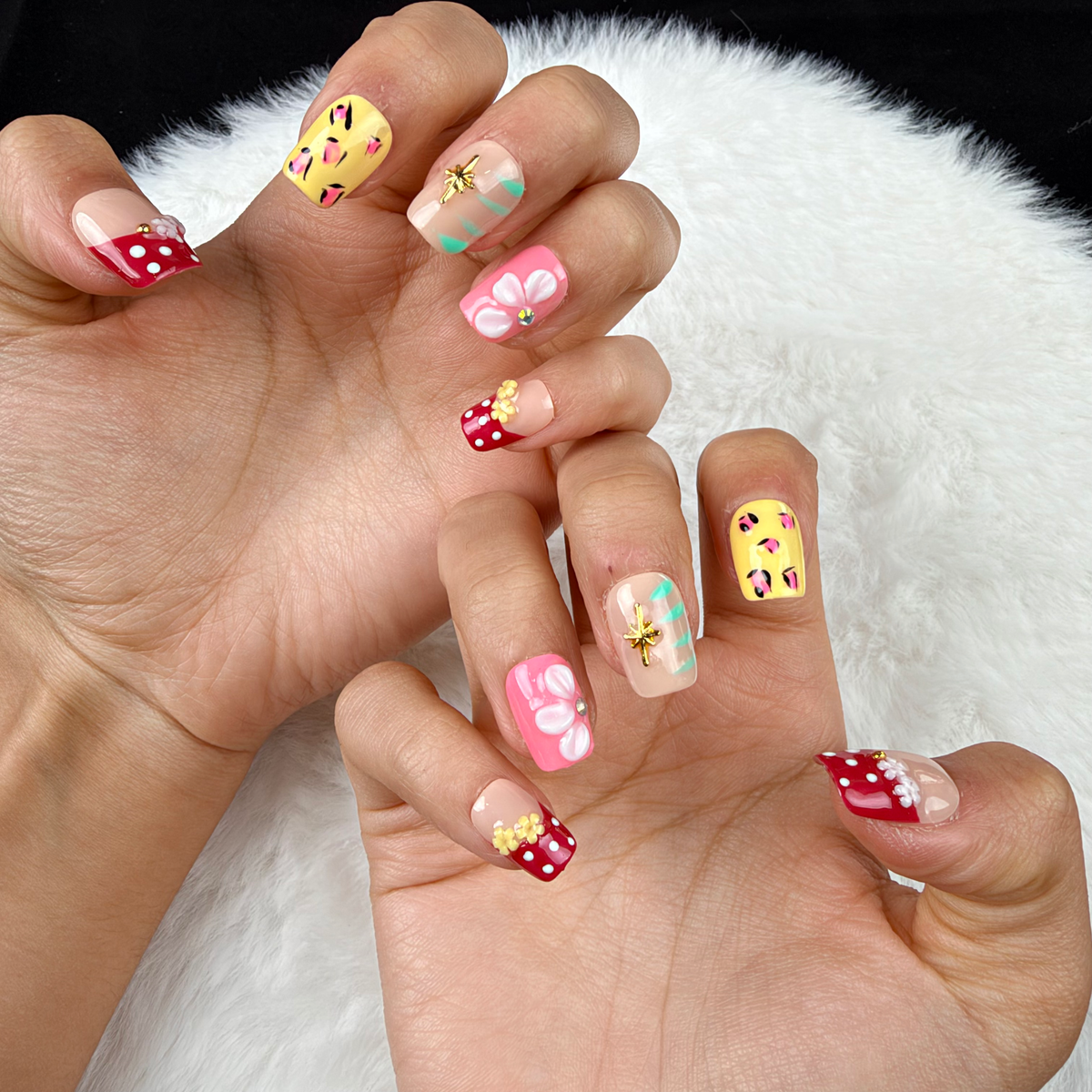 Close-up of hands wearing Garden Party red, yellow and pink floral square press-on nails