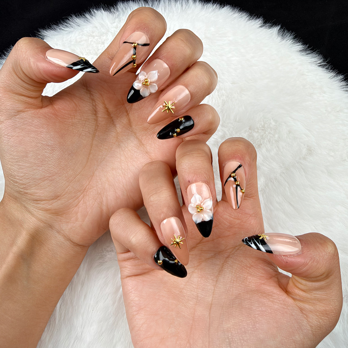 Close-up of hands wearing Starry Noir black French tip star and floral almond press-on nails