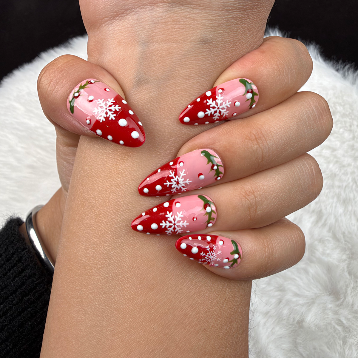 Close-up of hands wearing Holly Snow red and pink snowflake French tip Christmas almond press-on nails