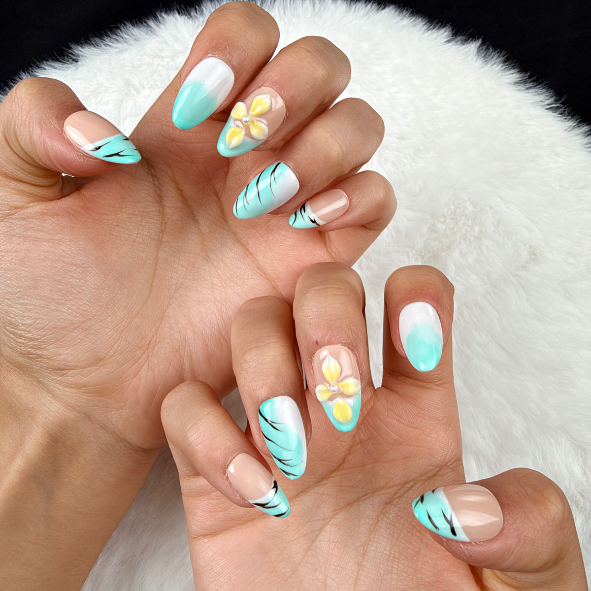Close-up of hands wearing Mint Breeze mint French tip and yellow floral almond press-on nails