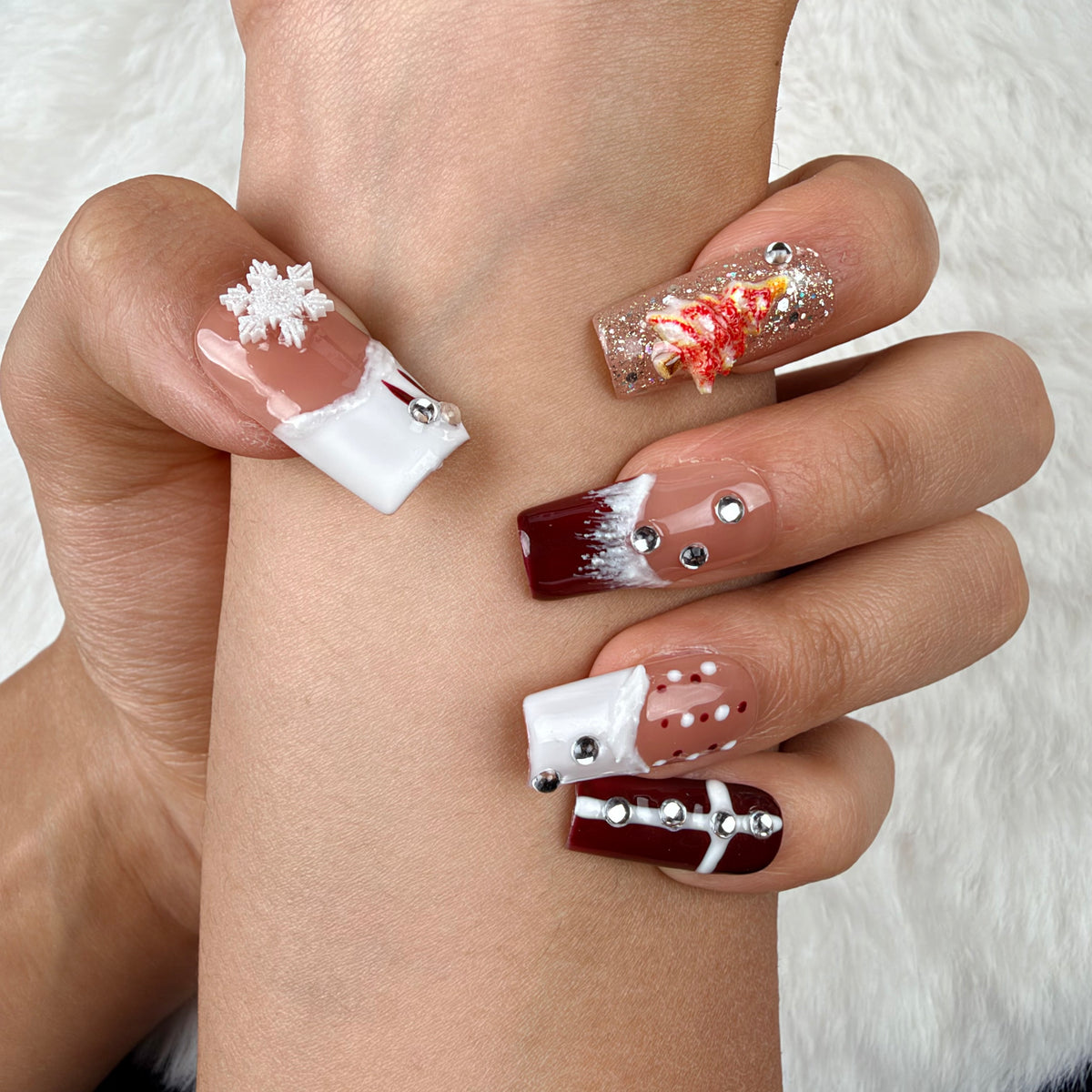 Hands wearing Winter Rose burgundy glitter and white snowflake Christmas square press-on nails