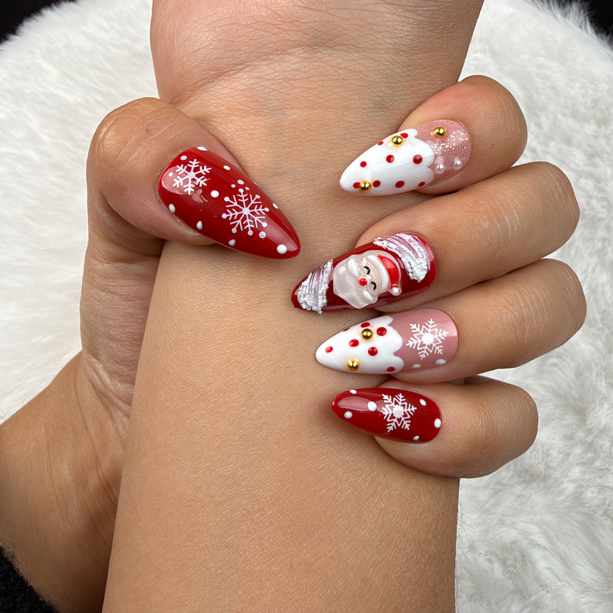 Close-up of hands wearing Santa Snow red and white Santa Christmas almond press-on nails