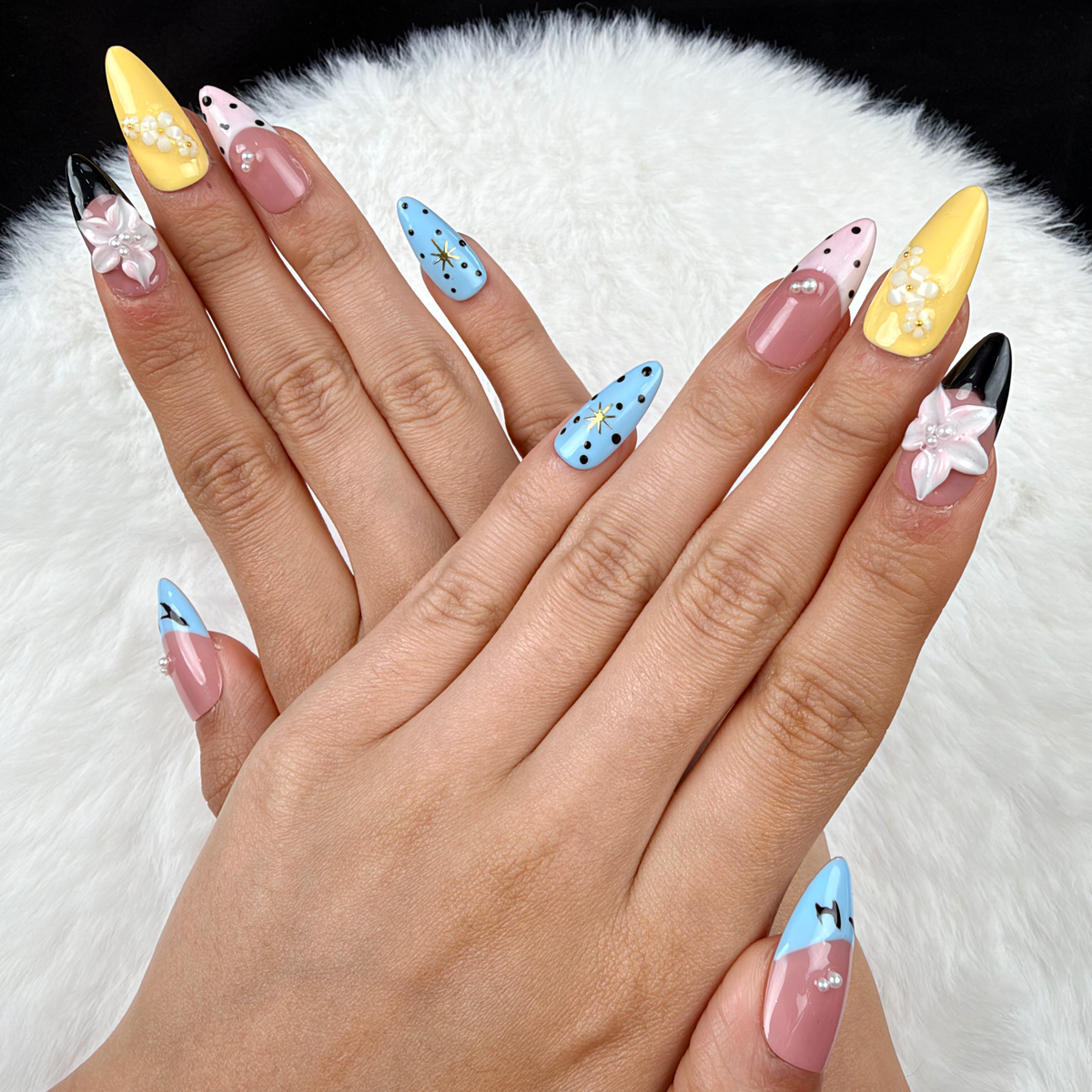 Hands wearing Pastel Graphic Garden blue, yellow and pink floral almond press-on nails