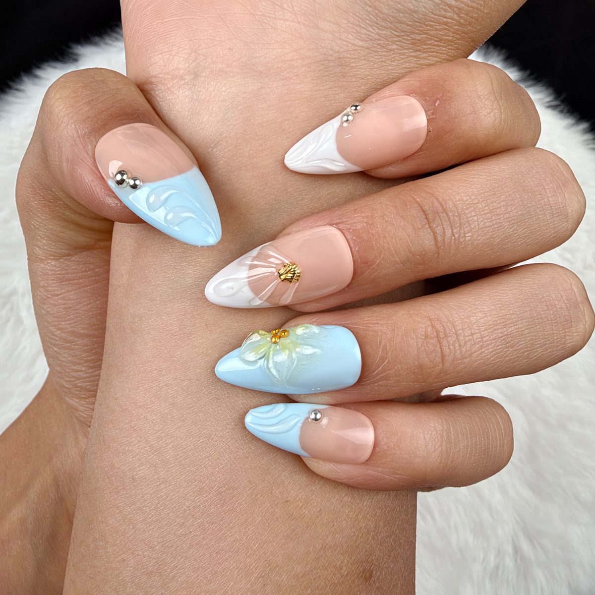 Detail shot of Seaside Petals light blue and nude shell floral almond press-on nails on hand