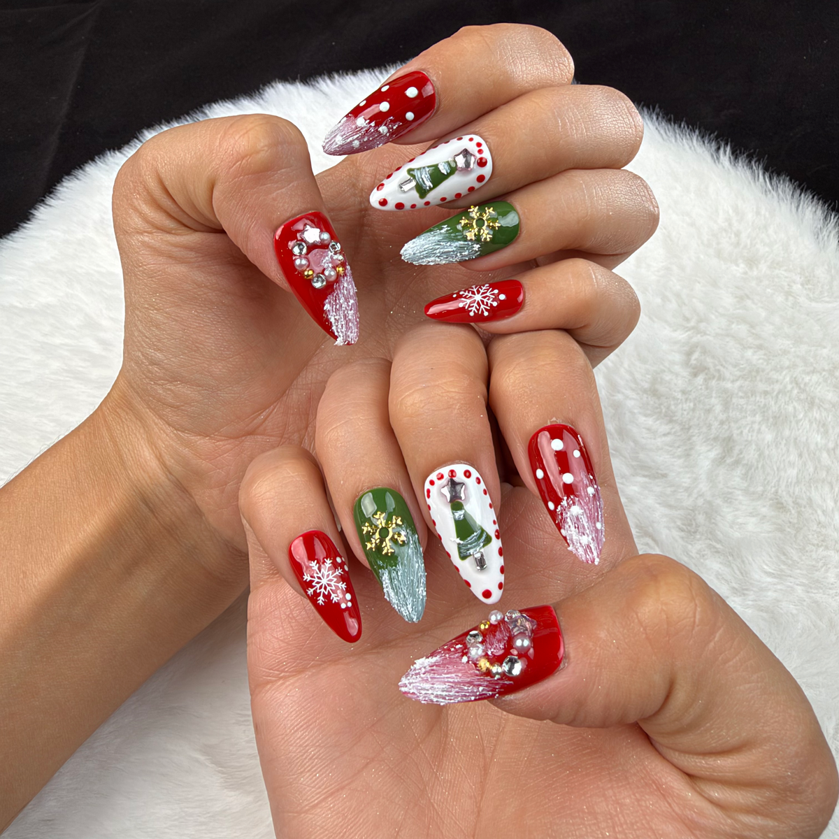 Hands wearing Festive Garland red, green and white Christmas almond press-on nails with wreaths and snowflakes