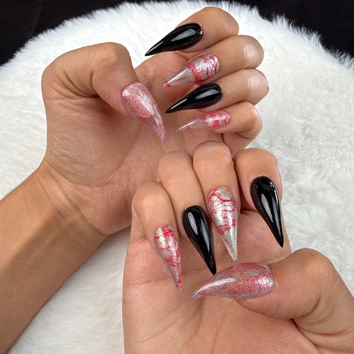 Hands wearing Rose Static pink and silver crackle and black stiletto press-on nails