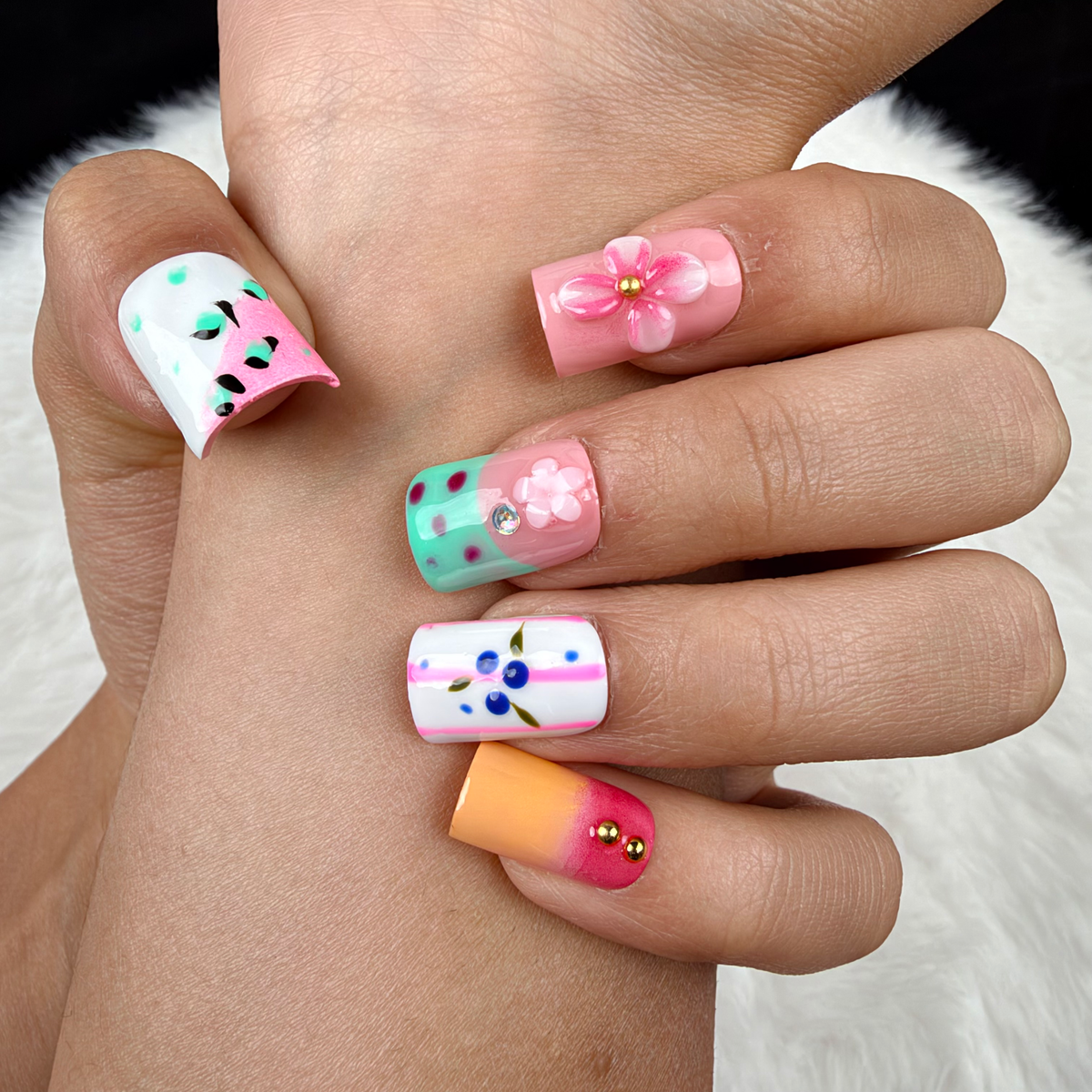 Detail shot of Pastel Flower Mix pink, mint and blue floral square press-on nails on hand