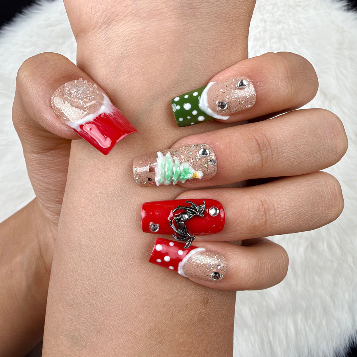 Close-up of hands wearing Gingerbread Party red, green and glitter Christmas square press-on nails with gingerbread and tree designs