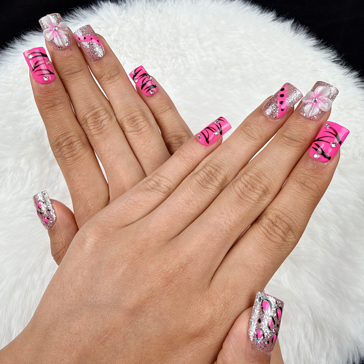 Hands wearing Pink Spark hot pink, black and silver floral square press-on nails