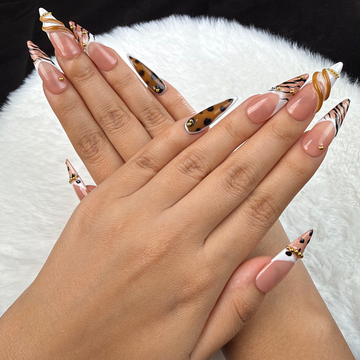 Close-up of hands wearing Wild French animal print French tip almond press-on nails with gold accents