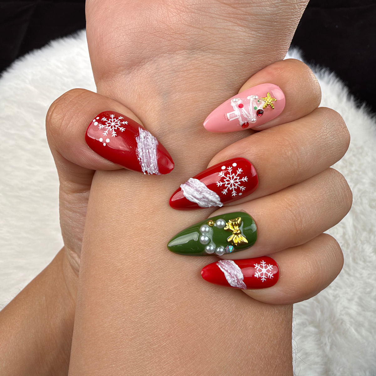 Close-up of hands wearing Evergreen Ribbon red, pink and green snowflake Christmas almond press-on nails