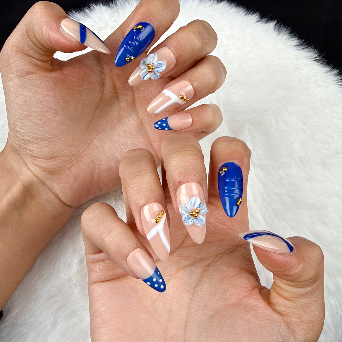 Close-up of hands wearing Cobalt Petal cobalt blue and nude floral almond press-on nails