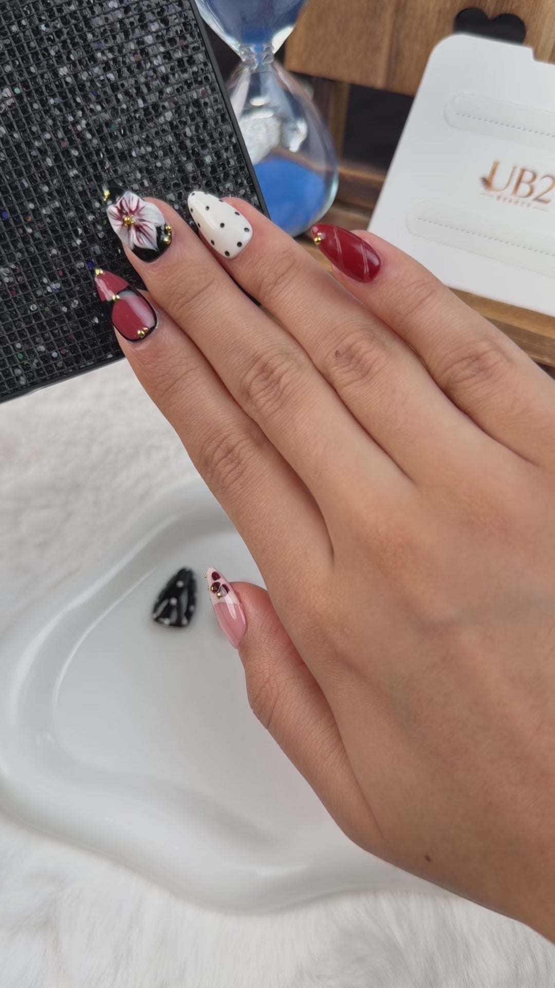 Load video: Step-by-step application of Burgundy and black 3D floral medium almond press-on nails with white flowers