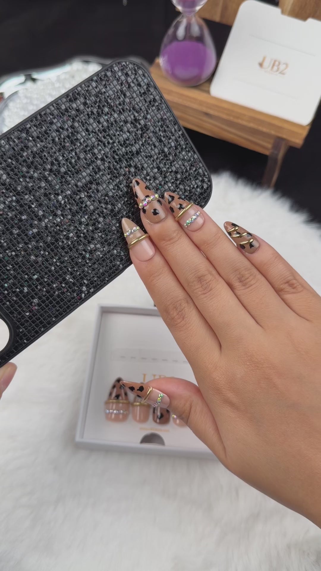 Load video: Step-by-step application of Wild Gleam nude leopard print almond press-on nails with gold accents and rhinestones