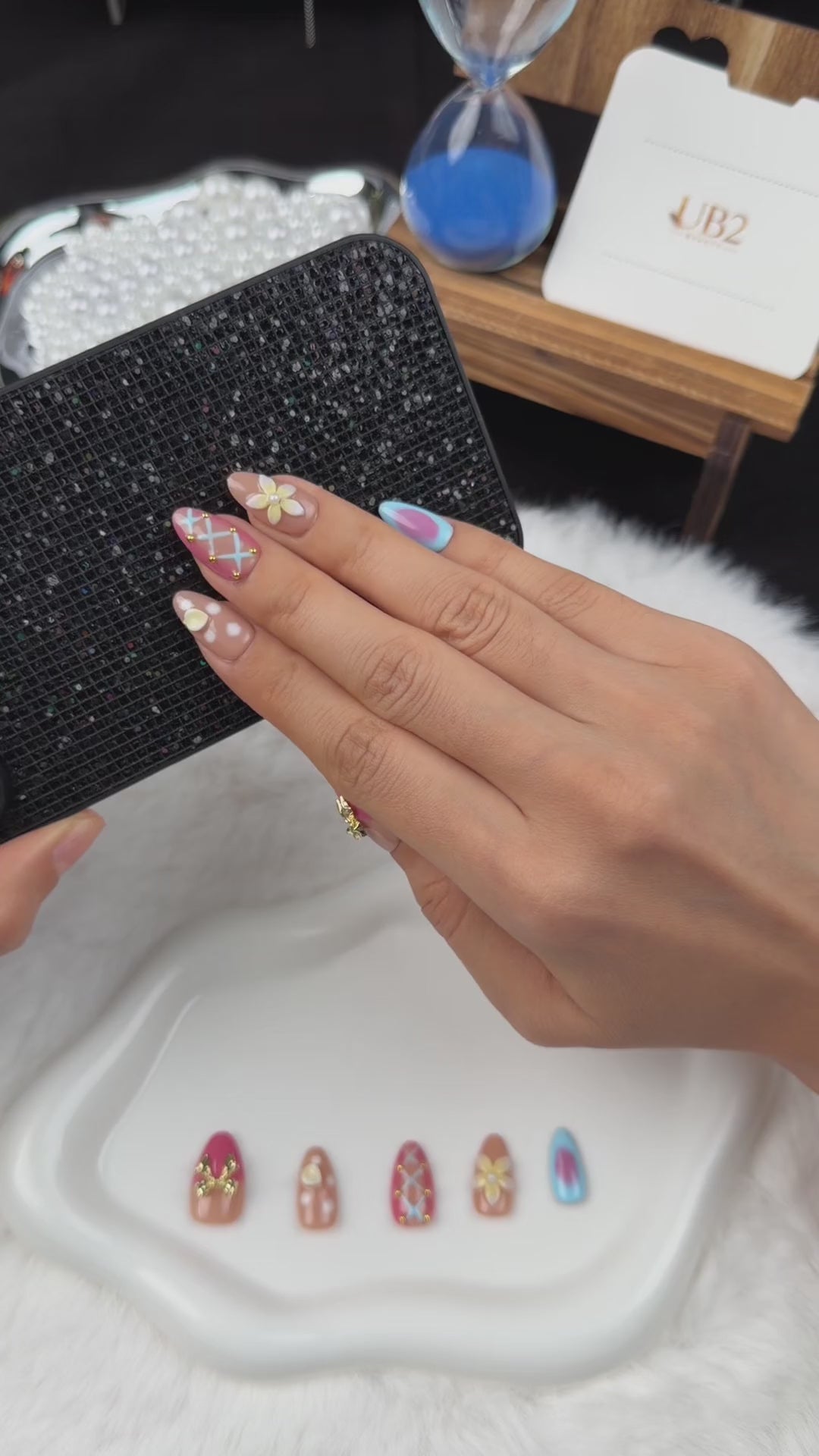 Load video: Step-by-step application of Sorbet Charms pink, blue and peach floral almond press-on nails with gold charms