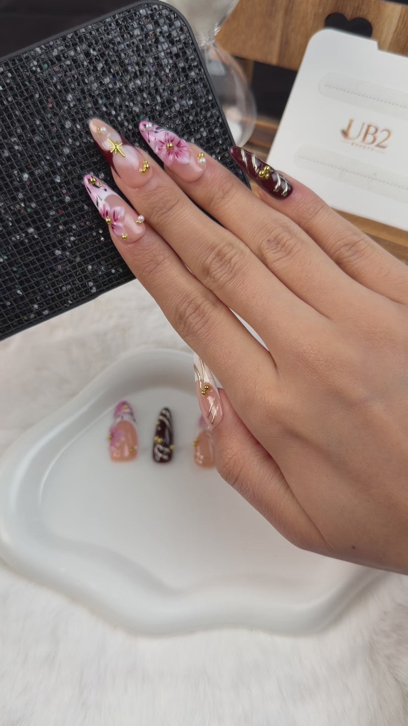 Step-by-step application of Blush and wine red floral bow almond press-on nails with gold details